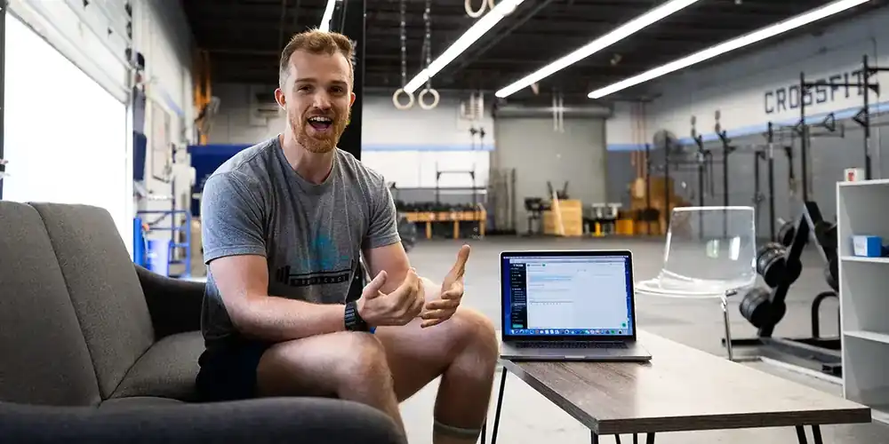 Un dueño de gimnasio revisando números y planificación dentro del gimnasio, representando la realidad empresarial del negocio.
