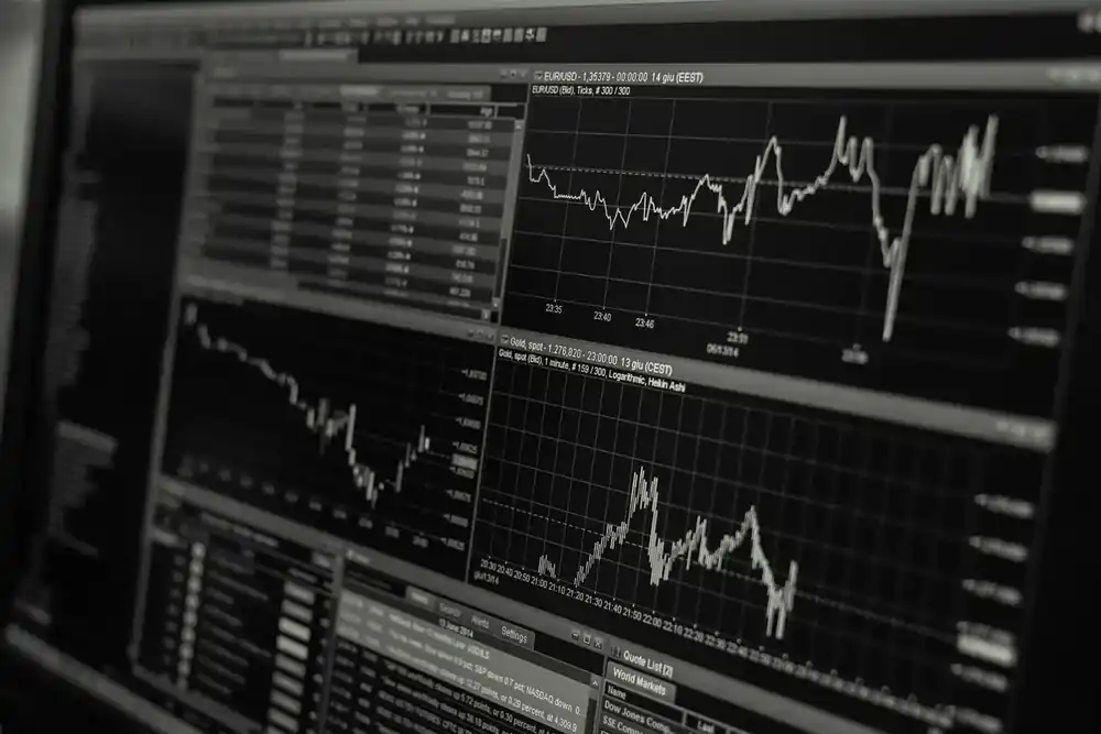 Pantallas de análisis financiero mostrando gráficas de trading con fluctuaciones de mercado en tiempo real, en una interfaz oscura con múltiples indicadores y líneas de tendencia.