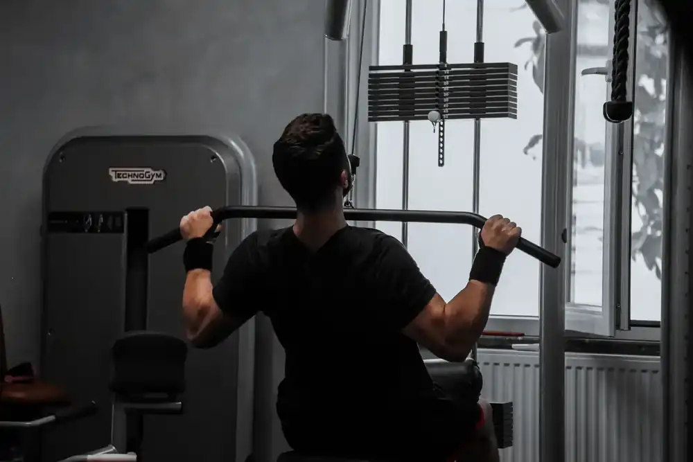 Persona realizando una rutina de entrenamiento en máquina de fuerza en un gimnasio moderno, enfocada en la ejecución del ejercicio con intensidad y control.