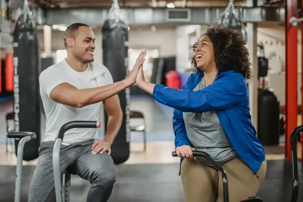 Coach celebra el avance de una socia durante una sesión de entrenamiento en el gimnasio. Coach celebra el avance de una socia durante una sesión de entrenamiento en el gimnasio.