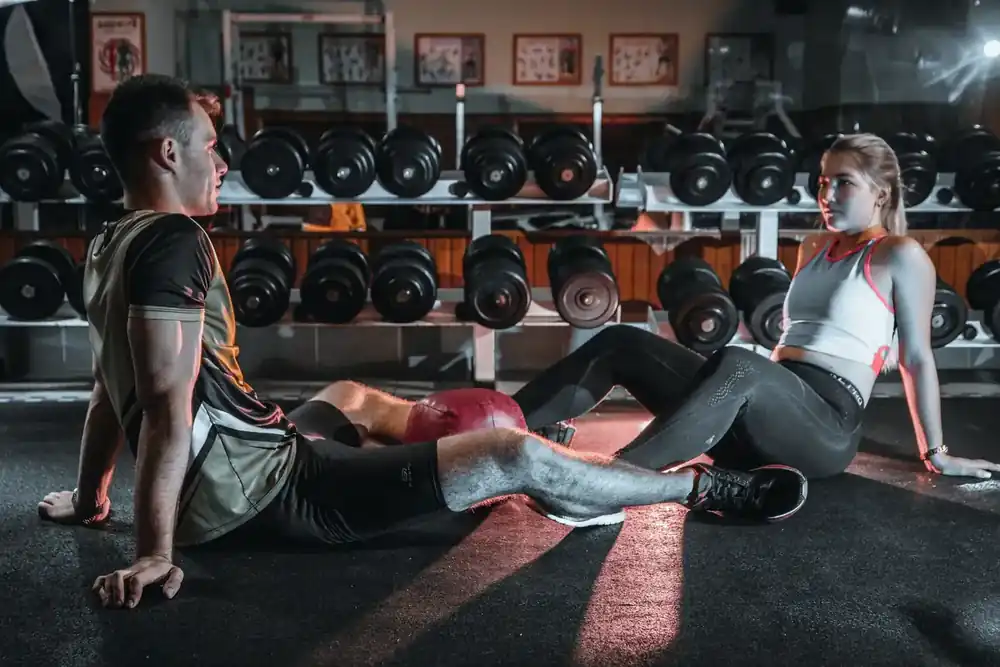 Dos socios conversando dentro del área de entrenamiento de un gimnasio.