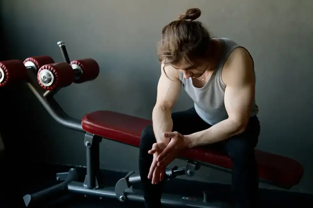 Socio sentado solo junto a una máquina de gimnasio después de entrenar. Socio sentado solo junto a una máquina de gimnasio después de entrenar.